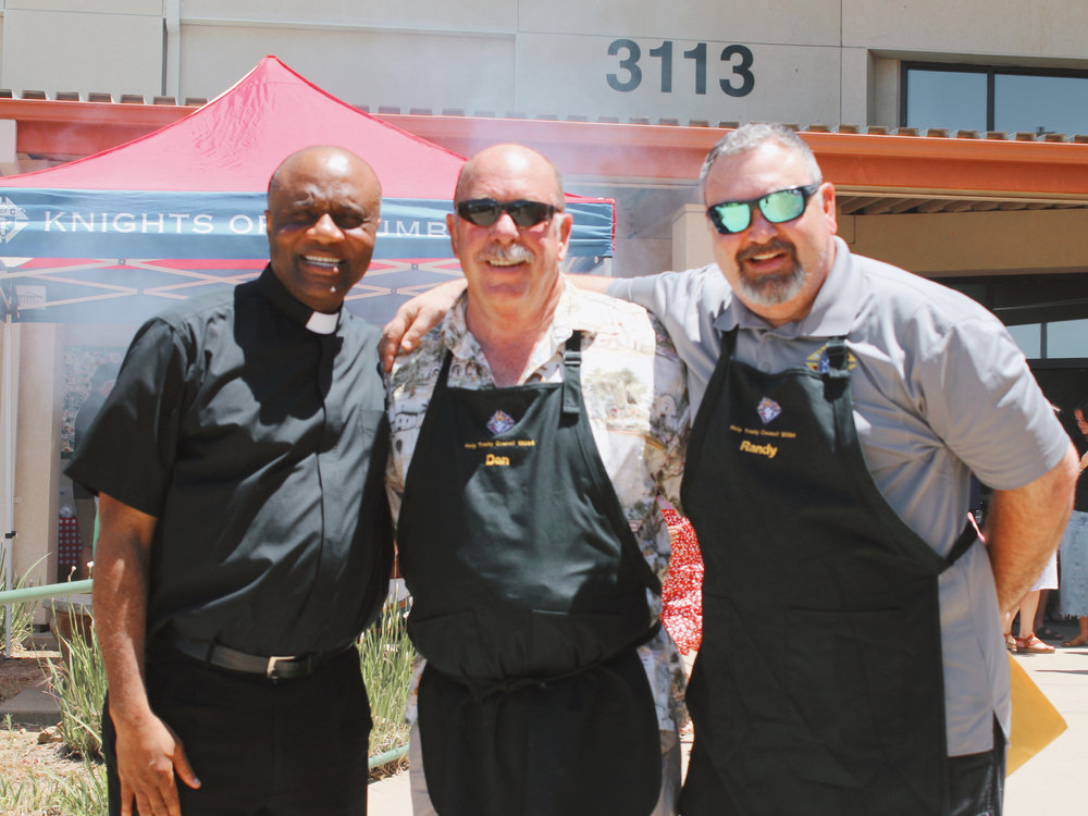 Fr. Vic and parishioners smiling together at a Holy Trinity Parish community barbecue